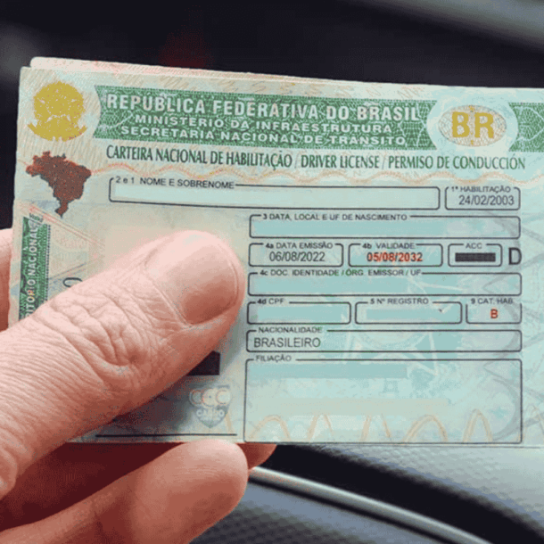 Close-up de uma mão segurando uma CNH brasileira. A imagem ilustra o conteúdo sobre como renovar CNH PE.