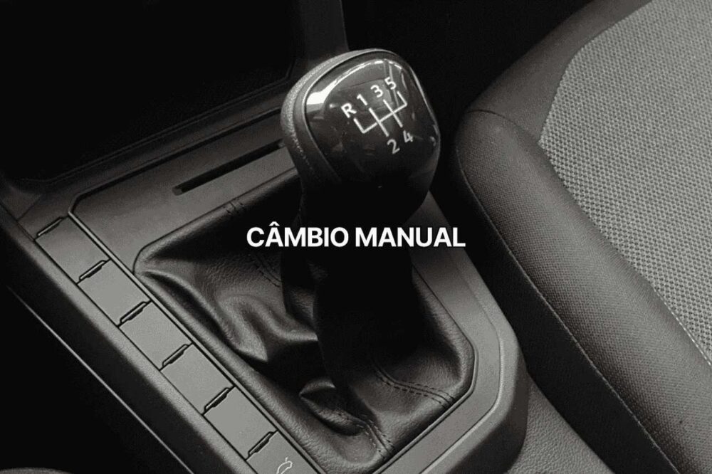Close no interior de um carro mostrando o câmbio manual com as posições das marchas visíveis, incluindo ré e cinco marchas à frente.