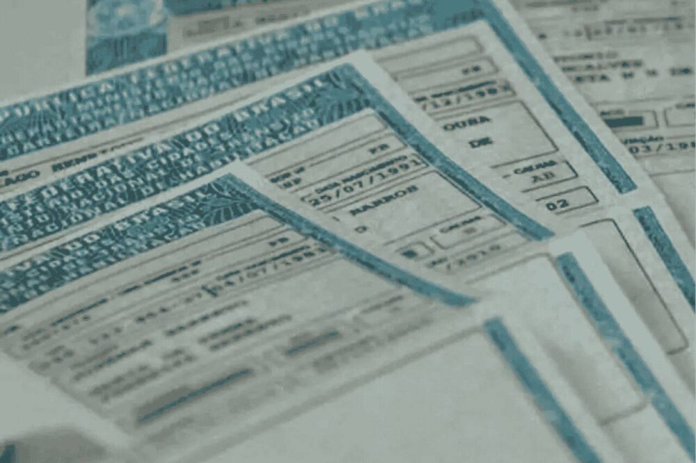 Carteiras de motorista brasileiras empilhadas, destacando dados como nome e data de validade.