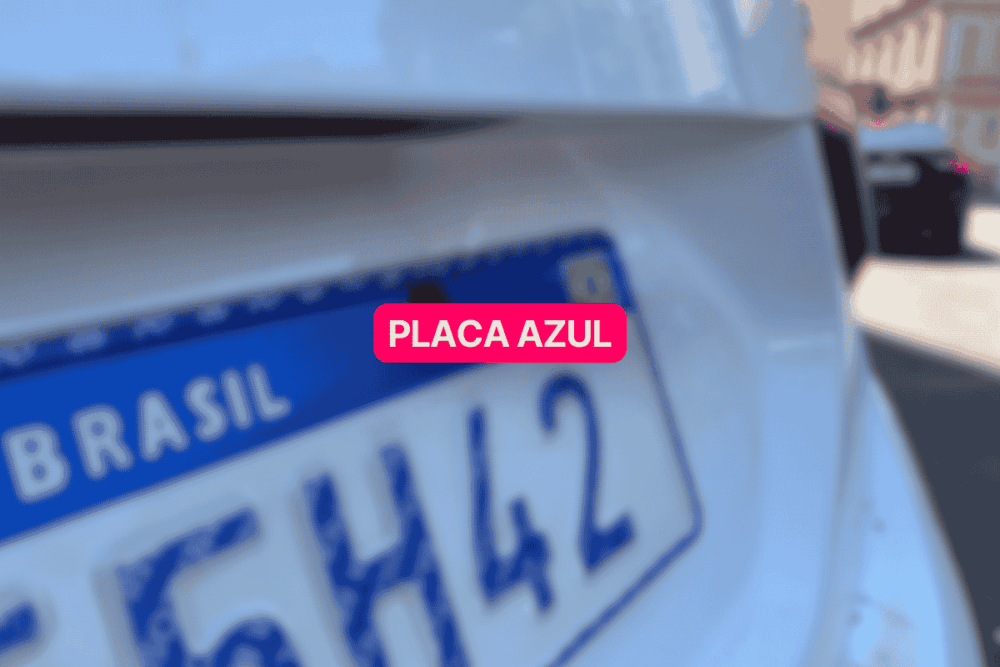 Close na traseira de um carro branco com placa azul do padrão Mercosul em destaque, parcialmente desfocada, com a palavra "Brasil" visível. A imagem representa o novo modelo de identificação veicular adotado no Brasil.