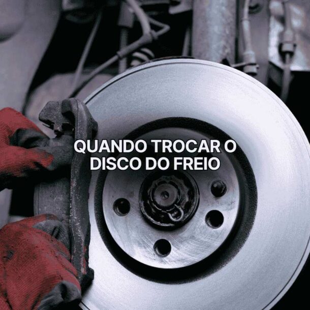 Mecânico usando luvas vermelhas removendo a pinça do freio dianteiro de um carro, expondo disco metálico brilhante. A imagem mostra inspeção detalhada para identificar quando trocar disco de freio desgastado.
