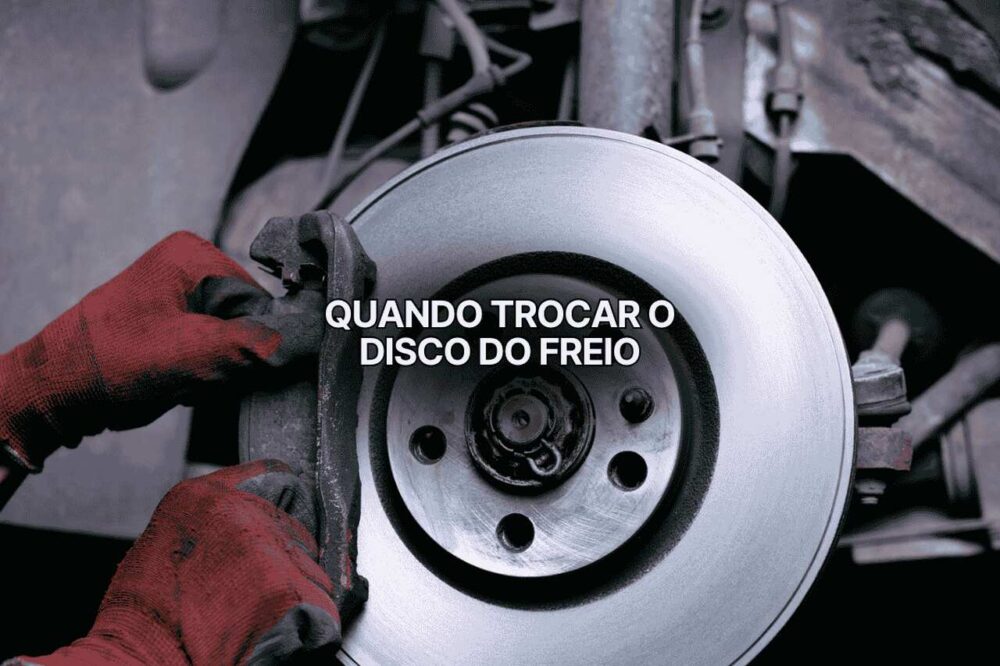 Mecânico usando luvas vermelhas removendo a pinça do freio dianteiro de um carro, expondo disco metálico brilhante. A imagem mostra inspeção detalhada para identificar quando trocar disco de freio desgastado.
