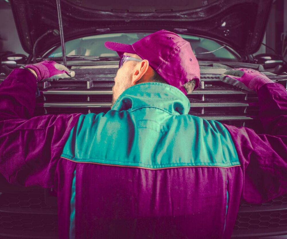 Imagem de um mecânico escutando barulho no carro na parte da frente
