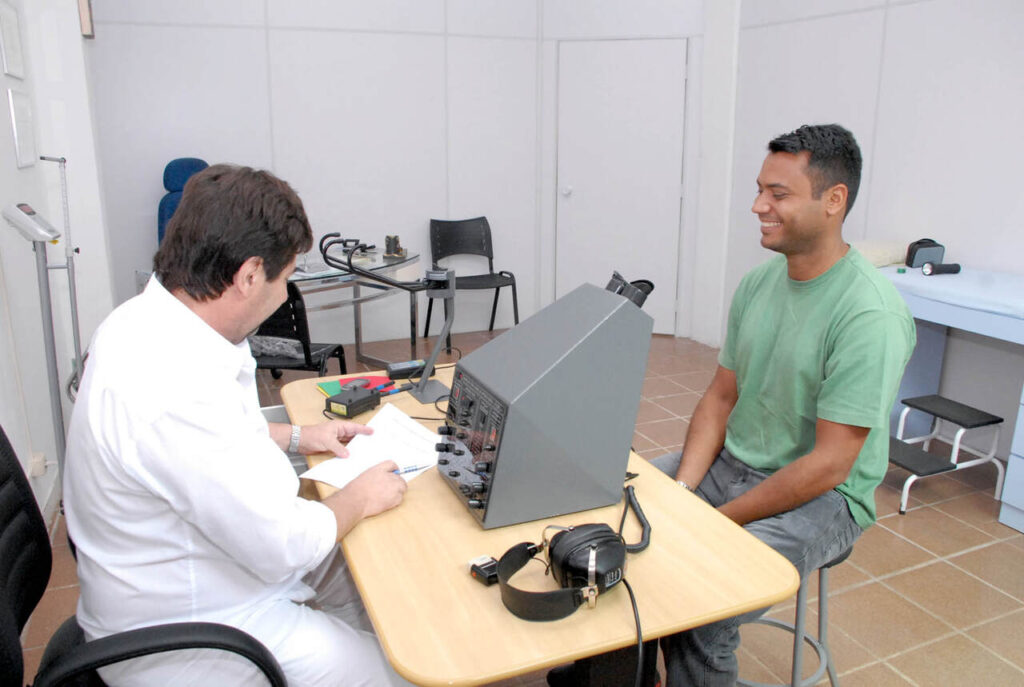Homem realiza exame de vista do DETRAN com profissional, usando equipamento oftalmológico em consultório durante o exame médico para CNH.