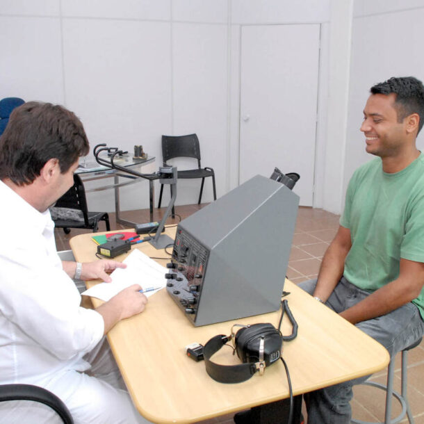 Homem realiza exame de vista do DETRAN com profissional, usando equipamento oftalmológico em consultório durante o exame médico para CNH.