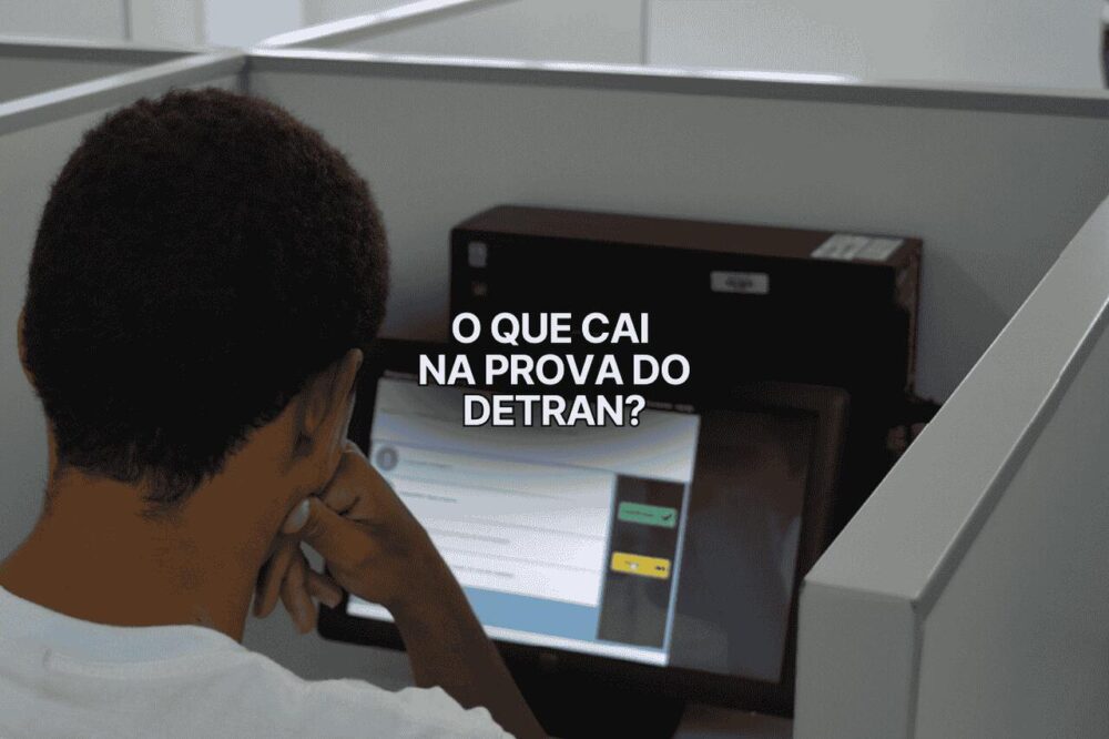 Homem faz prova teórica no computador em cabine individual com a frase "o que cai na prova do DETRAN?" sobreposta na tela.