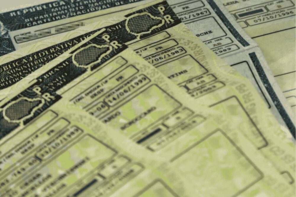 Diversas carteiras de habilitação antigas do Paraná empilhadas, ilustrando o processo de renovar CNH PR.