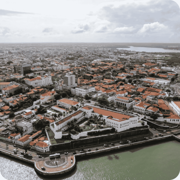Centro histórico com construções coloniais de telhado vermelho, margeando um canal com carros estacionados — preservação do patrimônio e licenciamento 2025 em áreas urbanas tradicionais do Maranhão.