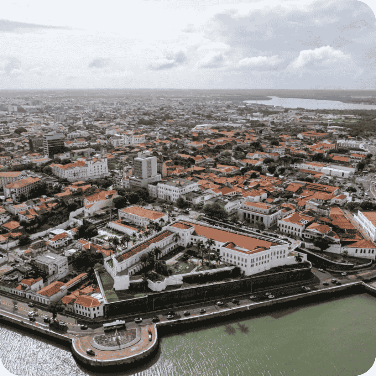 Centro histórico com construções coloniais de telhado vermelho, margeando um canal com carros estacionados — preservação do patrimônio e licenciamento 2025 em áreas urbanas tradicionais do Maranhão.