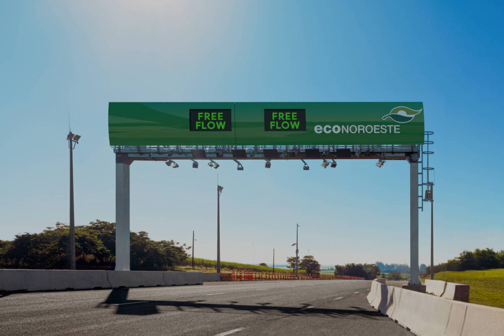 Pórtico moderno de pedágio eletrônico Free Flow em uma rodovia no interior de SP, administrada pela concessionária EconoNoroeste, ilustrando o conteúdo sobre como pagar pedágio free flow em SP. Estrutura verde com painéis escritos “FREE FLOW” e câmeras para leitura de placas, permitindo o pagamento automático sem necessidade de parar o veículo.