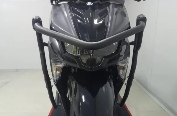Visão frontal de moto escura com protetor de carenagem envolvente, cobrindo os faróis e parte frontal do chassi para proteção em quedas.