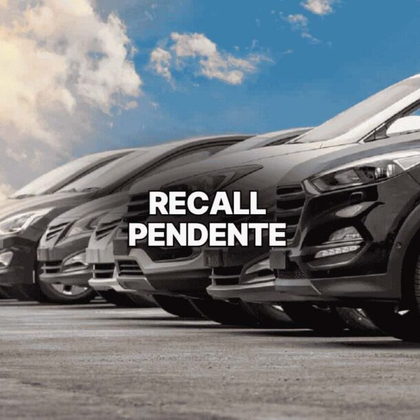 Imagem de vários carros estacionados em fila sob céu azul com nuvens, acompanhada do texto “recall pendente” em destaque central, alertando sobre a necessidade de verificar pendências veiculares.
