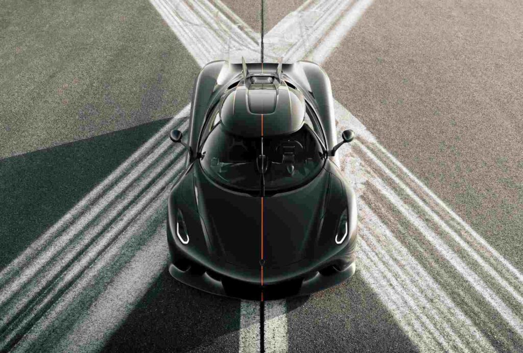 Visão aérea frontal de um hipercarro preto alinhado em pista de corrida, destacando formas simétricas, faróis modernos e traços laranja, representando o carro mais rápido do mundo em estilo impactante e exclusivo.