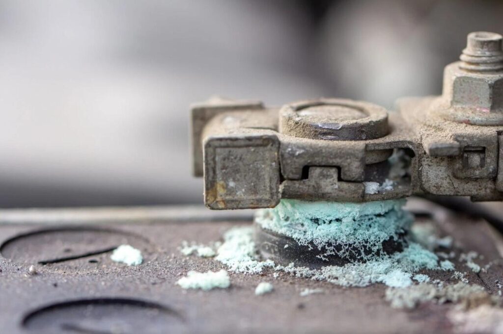 Detalhe de polo de bateria de carro com zinabre esverdeado acumulado, um dos sinais mais comuns de que a bateria do carro está ruim.
