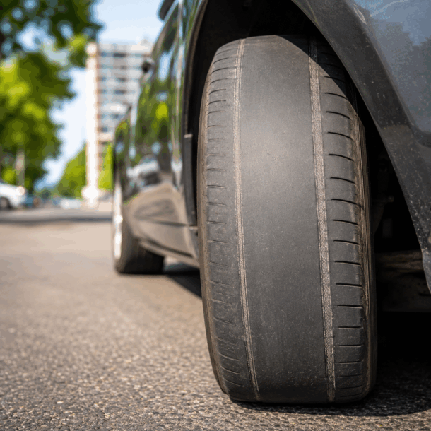 Pneu careca de carro com sulcos desgastados em contato com o asfalto