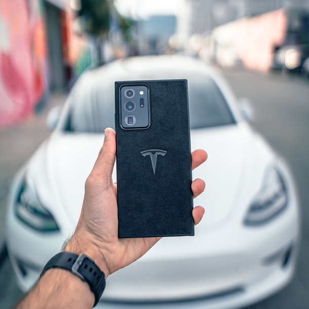 Pessoa segura um celular diante de um carro durante uma consulta digital de dados veiculares.