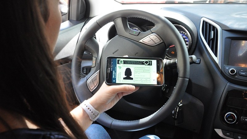 Pessoa consulta a CNH digital pelo celular dentro do carro.