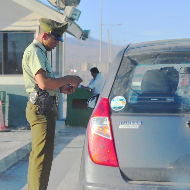 Agente confere os documentos de um motorista durante fiscalização em posto de controle.