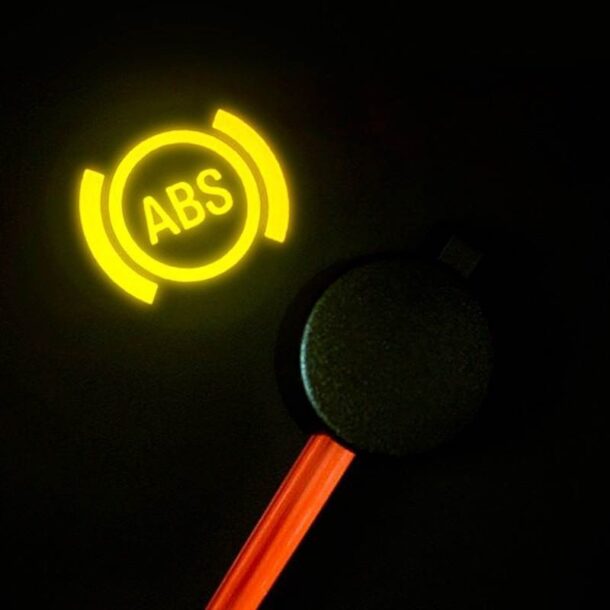Luz amarela do ABS acesa no painel do carro, indicando possível falha no sistema de freios antitravamento.