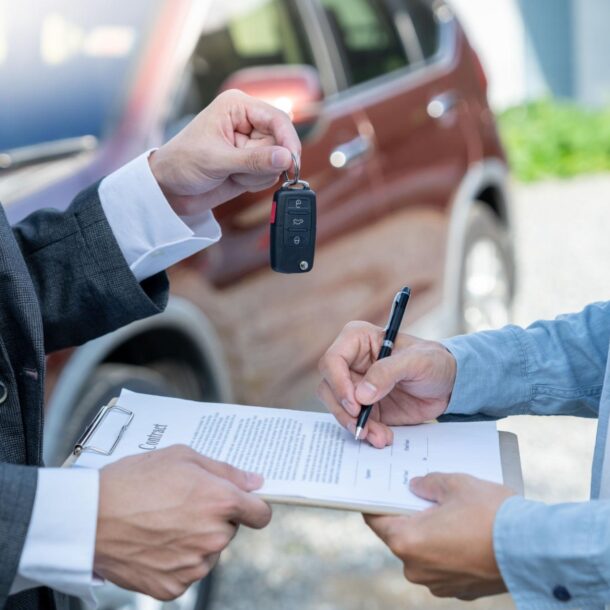Comprador assina contrato de compra e venda enquanto recebe a chave do veículo do vendedor.